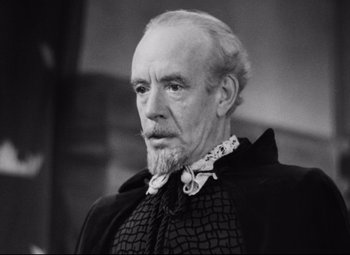 Movie still from “Queen Christina” (1933), directed by Rouben Mamoulian – An older man with a long beard wearing a black and white outfit; Close Up shot, Low angle