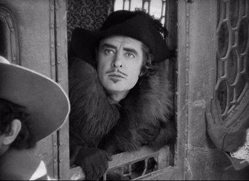 Movie still from “Queen Christina” (1933), directed by Rouben Mamoulian – A black and white photo of a man wearing a hat; Medium shot, Over the shoulder angle