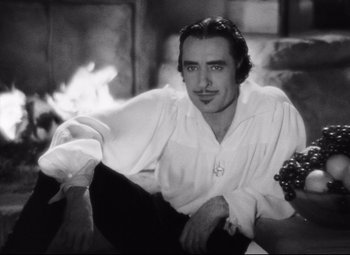 Movie still from “Queen Christina” (1933), directed by Rouben Mamoulian – Black and white photograph of a man sitting on a couch; Medium shot, High angle