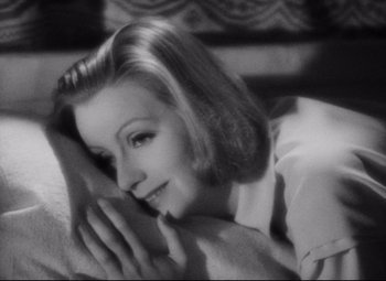 Movie still from “Queen Christina” (1933), directed by Rouben Mamoulian – A black - and - white photo of a woman laying on a couch; Close Up shot, High angle