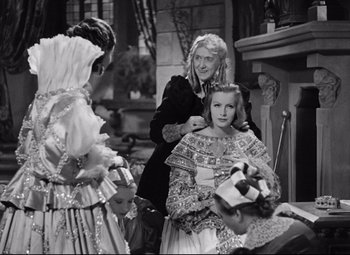 Movie still from “Queen Christina” (1933), directed by Rouben Mamoulian – A woman is cutting the hair of another woman in front of a fireplace; Medium shot, Over the shoulder angle