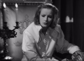 Movie still from “Queen Christina” (1933), directed by Rouben Mamoulian – A black and white photo of a woman sitting in front of a candle; Close Up shot, Over the shoulder angle