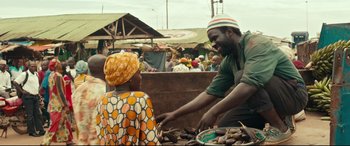 Movie still from “Queen of Katwe” (2016), directed by Mira Nair – A man and a woman are talking to each other in an open air market; Medium shot, Over the shoulder angle