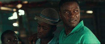 Movie still from “Queen of Katwe” (2016), directed by Mira Nair – Two men standing next to each other wearing hats; Close Up shot, Over the shoulder angle