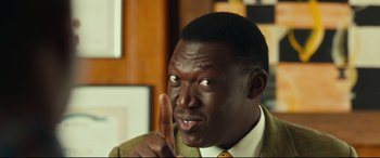 Movie still from “Queen of Katwe” (2016), directed by Mira Nair – A person holding a finger up; Close Up shot, Over the shoulder angle