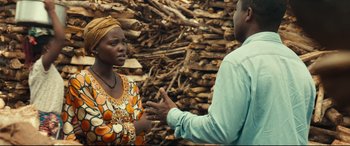 Movie still from “Queen of Katwe” (2016), directed by Mira Nair – A man and a woman talking in front of a pile of wood; Medium shot, Over the shoulder angle