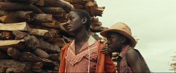 Movie still from “Queen of Katwe” (2016), directed by Mira Nair – Two young men standing next to a pile of wood; Close Up shot, Over the shoulder angle