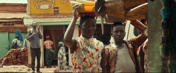 Movie still from “Queen of Katwe” (2016), directed by Mira Nair – A woman carrying bananas on top of her head; Medium shot, Low angle