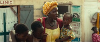Movie still from “Queen of Katwe” (2016), directed by Mira Nair – A woman and two children are standing together; Close Up shot, Over the shoulder angle