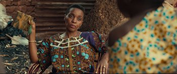 Movie still from “Queen of Katwe” (2016), directed by Mira Nair – An older woman sitting in a chair in front of a tree; Close Up shot, Over the shoulder angle