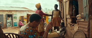 Movie still from “Queen of Katwe” (2016), directed by Mira Nair – A group of people standing on top of a wooden structure; Medium shot, Over the shoulder angle