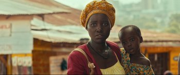Movie still from “Queen of Katwe” (2016), directed by Mira Nair – A woman wearing a yellow head scarf standing next to a child; Close Up shot, Low angle