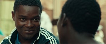 Movie still from “Queen of Katwe” (2016), directed by Mira Nair – Two young men sitting in front of each other talking; Close Up shot, Over the shoulder angle
