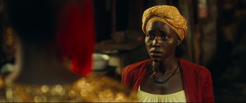 Movie still from “Queen of Katwe” (2016), directed by Mira Nair – A woman wearing a yellow head scarf and a yellow dress; Close Up shot, Over the shoulder angle