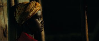 Movie still from “Queen of Katwe” (2016), directed by Mira Nair – A woman wearing a yellow head scarf is looking to the side; Close Up shot, Low angle