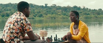 Movie still from “Queen of Katwe” (2016), directed by Mira Nair – Two people sitting at a table with chess pieces on it; Medium shot, Over the shoulder angle