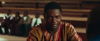 Movie still from “Queen of Katwe” (2016), directed by Mira Nair – A person wearing a striped shirt; Close Up shot, Over the shoulder angle