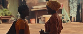 Movie still from “Queen of Katwe” (2016), directed by Mira Nair – Two women standing next to each other on a street; Medium shot, Over the shoulder angle