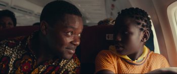 Movie still from “Queen of Katwe” (2016), directed by Mira Nair – A man and a woman sitting next to each other on a train; Close Up shot, Over the shoulder angle