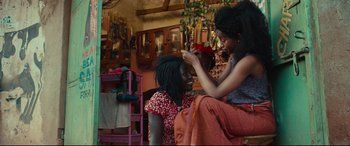Movie still from “Queen of Katwe” (2016), directed by Mira Nair – Two young women are sitting in a living room; Medium shot, Over the shoulder angle