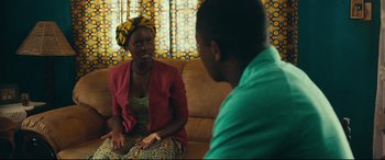 Movie still from “Queen of Katwe” (2016), directed by Mira Nair – A woman sitting on a couch talking to a man; Medium shot, Over the shoulder angle