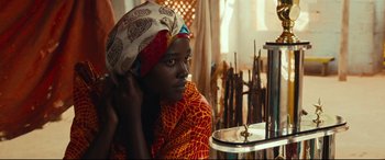 Movie still from “Queen of Katwe” (2016), directed by Mira Nair – A woman with a head scarf is sitting in front of a mirror; Close Up shot, Over the shoulder angle