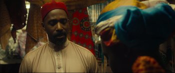 Movie still from “Queen of Katwe” (2016), directed by Mira Nair – A man wearing a red hat looking at another man wearing a red hat; Close Up shot, Over the shoulder angle