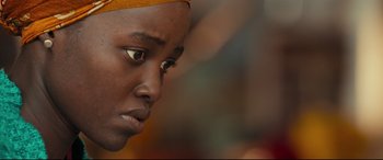 Movie still from “Queen of Katwe” (2016), directed by Mira Nair – A person's face with a yellow headscarf; Close Up shot, Over the shoulder angle