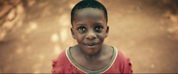 Movie still from “Queen of Katwe” (2016), directed by Mira Nair – A young boy with a red shirt; Extreme Close Up shot, High angle