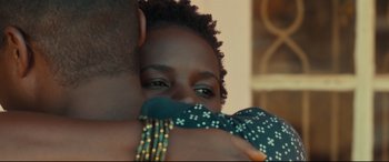 Movie still from “Queen of Katwe” (2016), directed by Mira Nair – A person hugging another person; Close Up shot, Over the shoulder angle