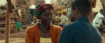 Movie still from “Queen of Katwe” (2016), directed by Mira Nair – A woman wearing a colorful head scarf talking to a man; Close Up shot, Over the shoulder angle