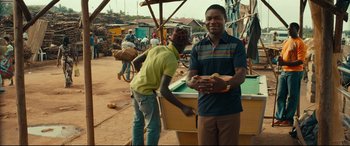 Movie still from “Queen of Katwe” (2016), directed by Mira Nair – A man standing next to a pool table; Medium shot, Over the shoulder angle