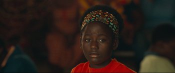 Movie still from “Queen of Katwe” (2016), directed by Mira Nair – A person wearing a head band; Close Up shot, Over the shoulder angle