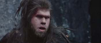 Movie still from “Quest for Fire” (1981), directed by Jean-Jacques Annaud – A person with long hair and a beard; Close Up shot, Low angle