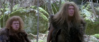 Movie still from “Quest for Fire” (1981), directed by Jean-Jacques Annaud – An image of a man that is walking in the woods; Medium shot, Low angle