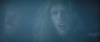 Movie still from “Quest for Fire” (1981), directed by Jean-Jacques Annaud – A person with long hair; Close Up shot, Over the shoulder angle