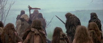 Movie still from “Quest for Fire” (1981), directed by Jean-Jacques Annaud – A group of people with long hair and beards; Wide shot, Low angle