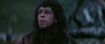 Movie still from “Quest for Fire” (1981), directed by Jean-Jacques Annaud – A person wearing a wig and a beard; Close Up shot, Low angle