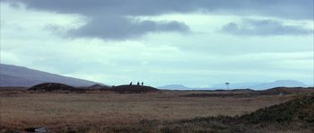 Movie still from “Quest for Fire” (1981), directed by Jean-Jacques Annaud – Two horses standing on top of a grassy hill under a cloudy sky; Extreme Wide shot, Low angle