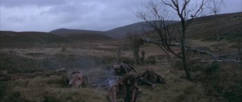 Movie still from “Quest for Fire” (1981), directed by Jean-Jacques Annaud – A group of people sitting on the ground next to a fire; Wide shot, High angle