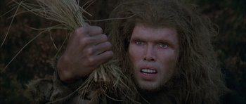 Movie still from “Quest for Fire” (1981), directed by Jean-Jacques Annaud – A person holding a bunch of grass; Close Up shot, Low angle
