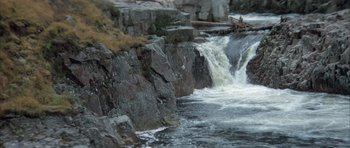 Movie still from “Quest for Fire” (1981), directed by Jean-Jacques Annaud – A small waterfall on the side of a river; Extreme Wide shot, High angle
