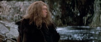 Movie still from “Quest for Fire” (1981), directed by Jean-Jacques Annaud – A man with long hair is standing in the snow; Close Up shot, Low angle