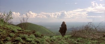 Movie still from “Quest for Fire” (1981), directed by Jean-Jacques Annaud – A person riding a horse on top of a green hill; Extreme Wide shot, Low angle