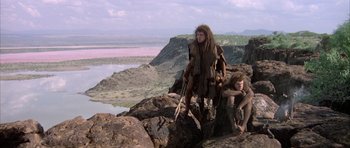 Movie still from “Quest for Fire” (1981), directed by Jean-Jacques Annaud – A couple of people standing on top of a mountain; Wide shot, High angle