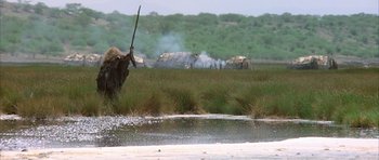 Movie still from “Quest for Fire” (1981), directed by Jean-Jacques Annaud – An elephant standing next to a body of water; Wide shot, Low angle