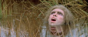 Movie still from “Quest for Fire” (1981), directed by Jean-Jacques Annaud – A man in a body of water looking up at the sky; Close Up shot, Overhead angle