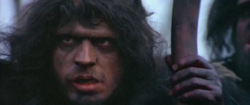 Movie still from “Quest for Fire” (1981), directed by Jean-Jacques Annaud – A person with a beard; Close Up shot, Low angle