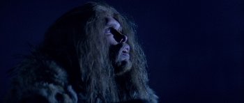 Movie still from “Quest for Fire” (1981), directed by Jean-Jacques Annaud – A man with long hair and a long beard; Close Up shot, Low angle
