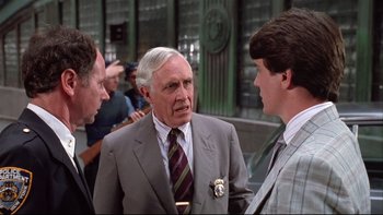 Movie still from “Quick Change” (1990), directed by Howard Franklin – A man in a suit talking to two other men; Close Up shot, Over the shoulder angle